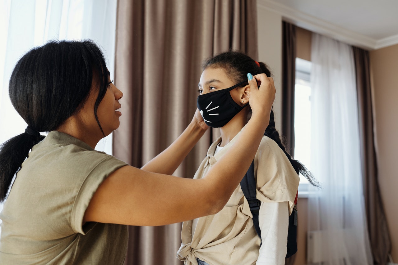 mother putting he daughter's mask on