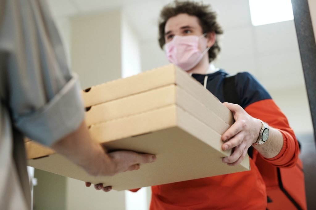 man handing over three boxes of pizza