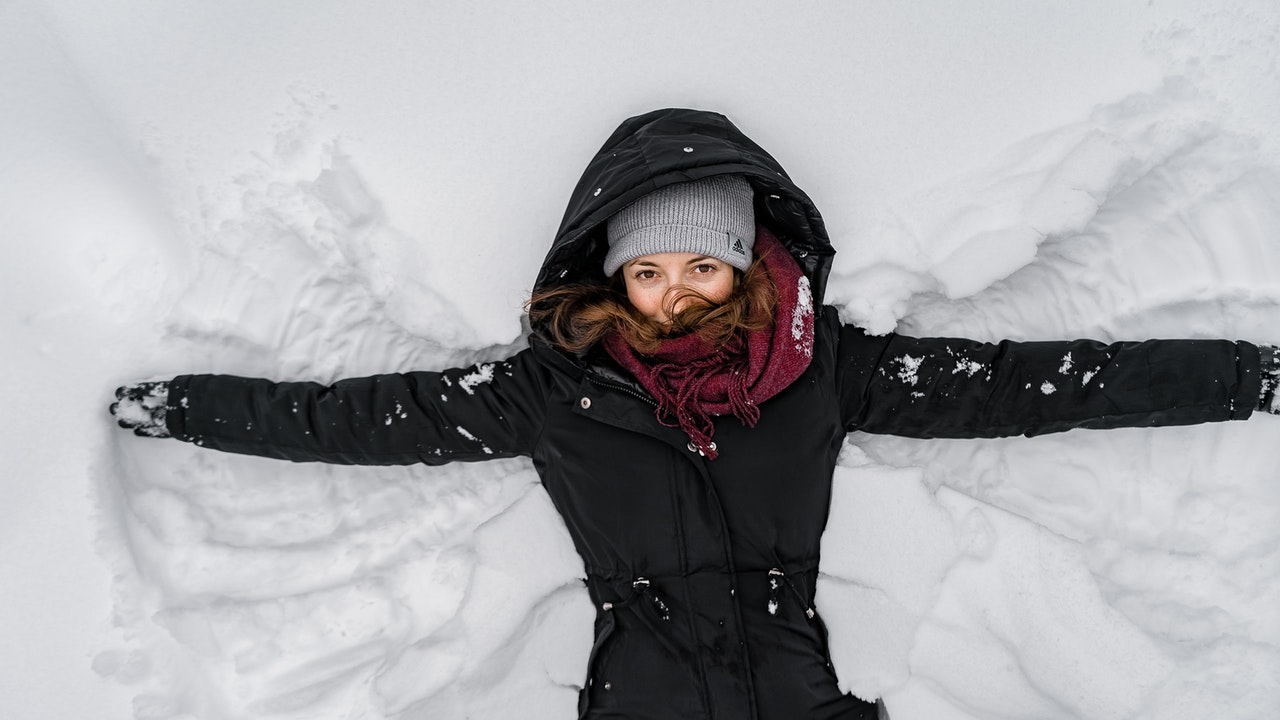 woman laying on the snow making snow angel