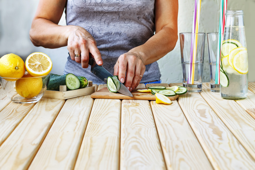 Woman slicing a lemon and cucumber for her drink