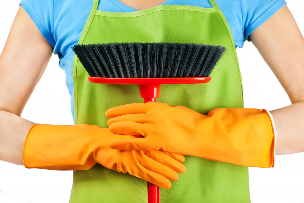 a person wearing an apron and gloves while holding a broom