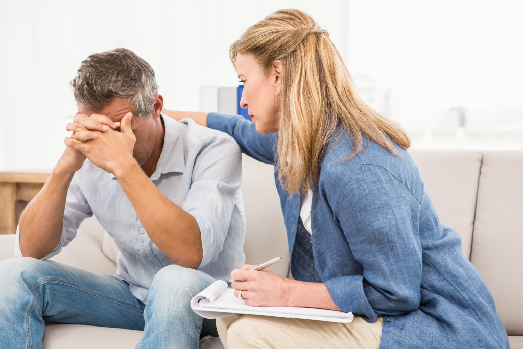 an anxious man getting comforted by a female psychiatrist