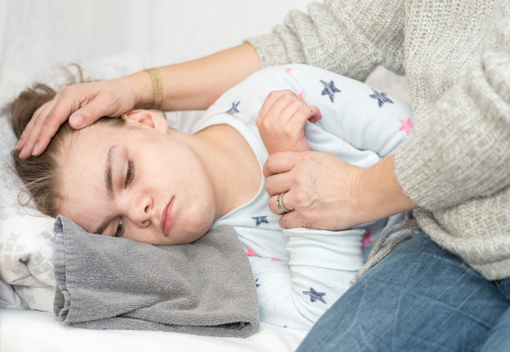 A sick child in bed being held by a parent