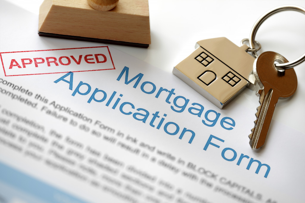 Mortgage loan application with the word approved stamped on it and a house key on top.