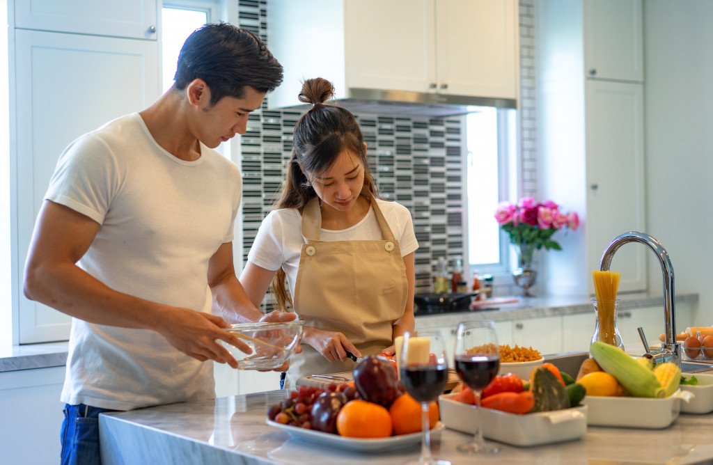 A fit and handsome man with a woman preparing healthy meals in the kitchen