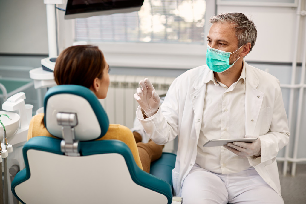 Dentist with face mask communicating with female patient 