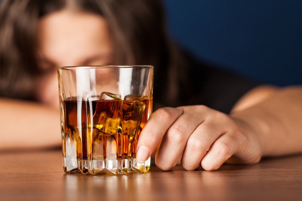 a woman looking depressed behind a glass of alcohol