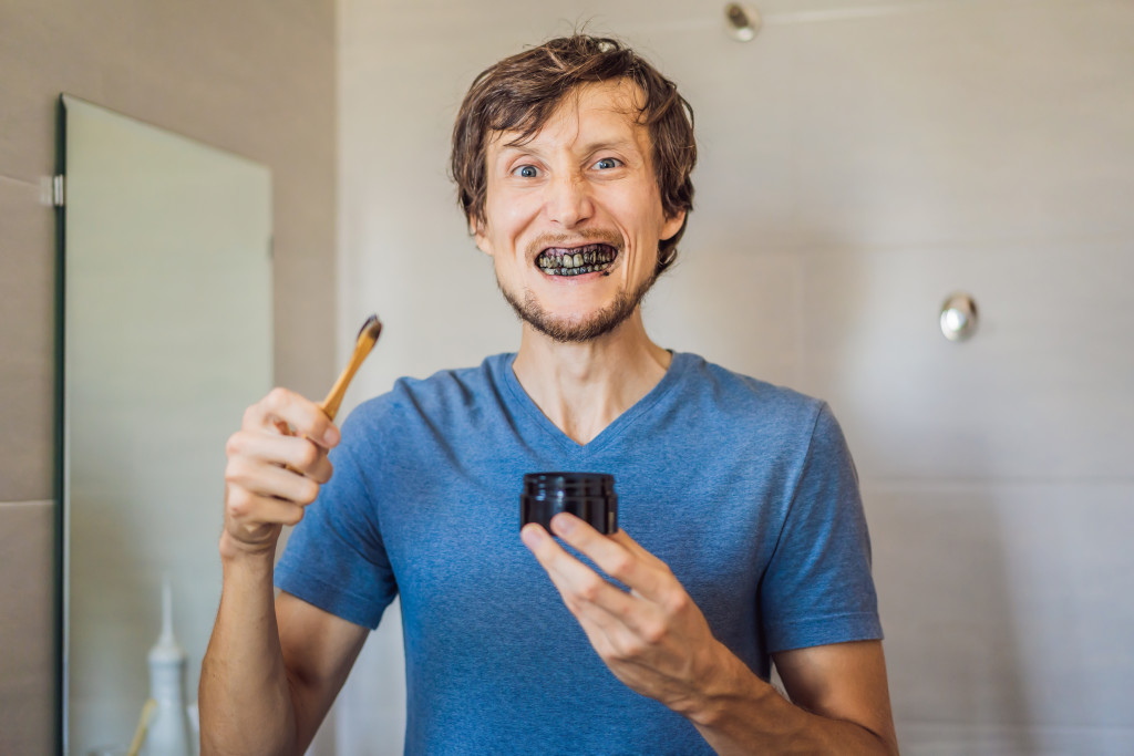 man using activated charcoal powder for brushing and whitening teeth