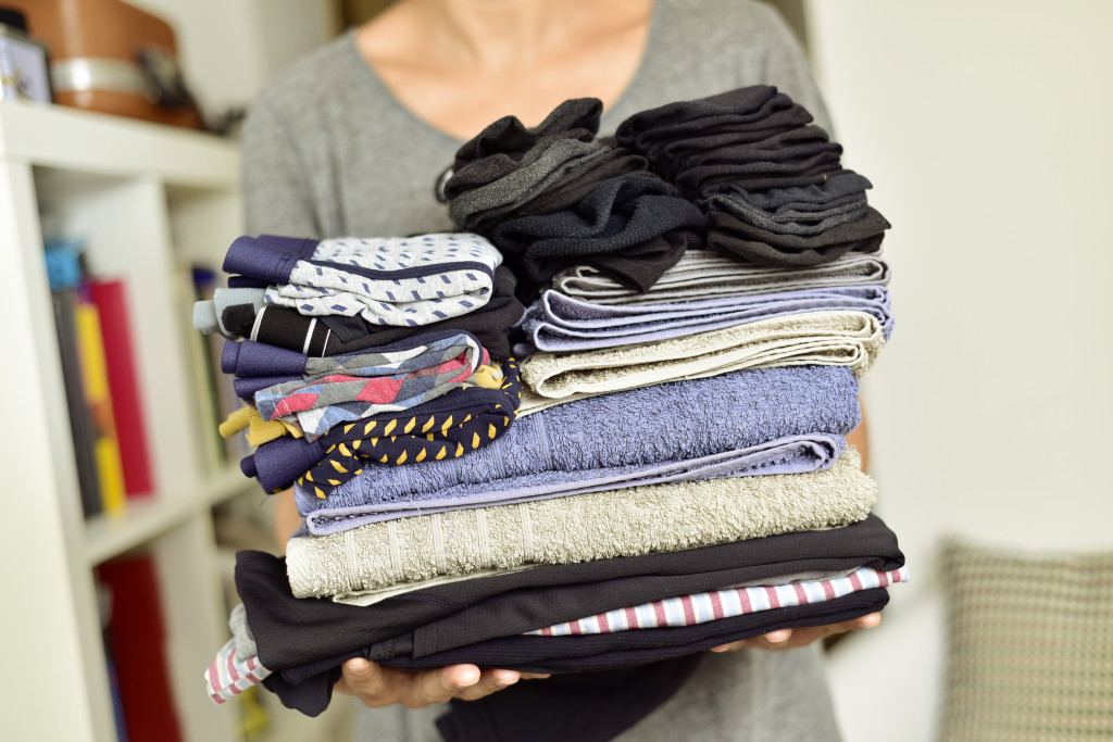 A woman carrying a pile of clean clothes to a room