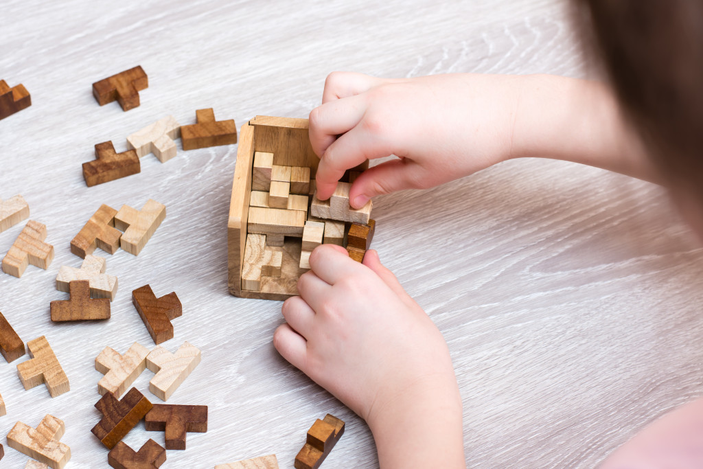 A child solving a wooden box puzzle on her own