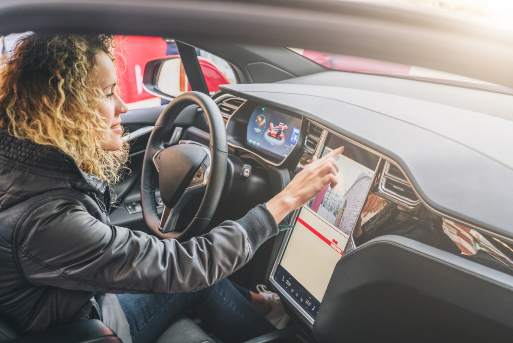 woman driving car while using tablet