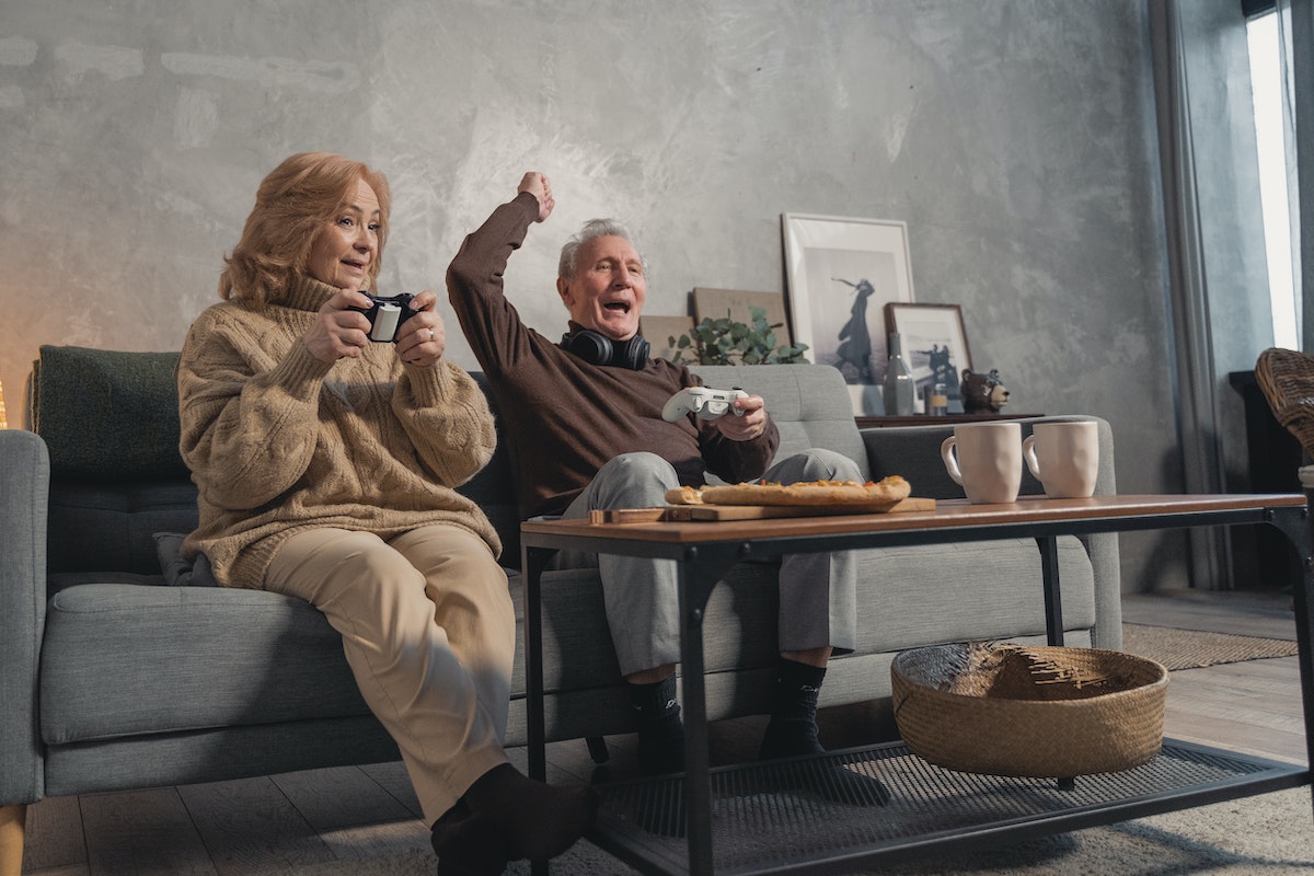 elderly couple sitting on couch while playing games