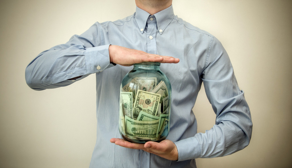 A man holding a jar of money