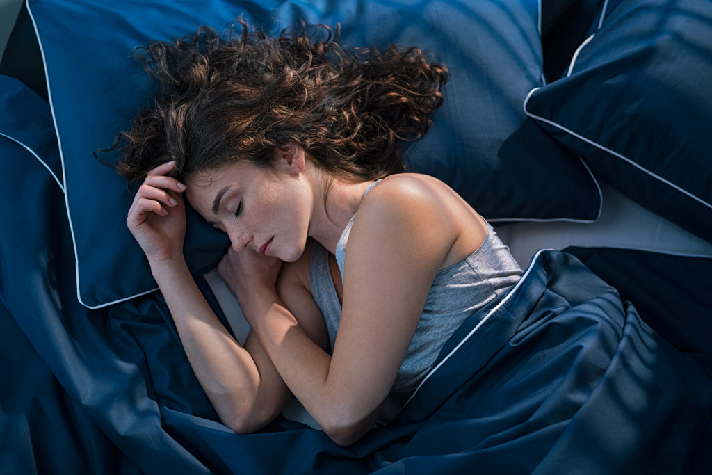 woman peacefully sleeping in blue silk bed