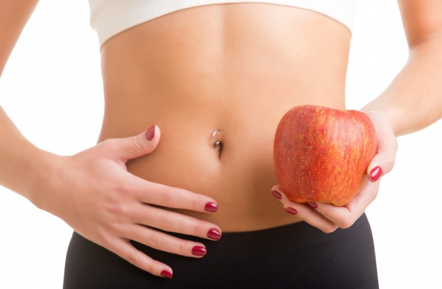 stomach of a woman holding an apple